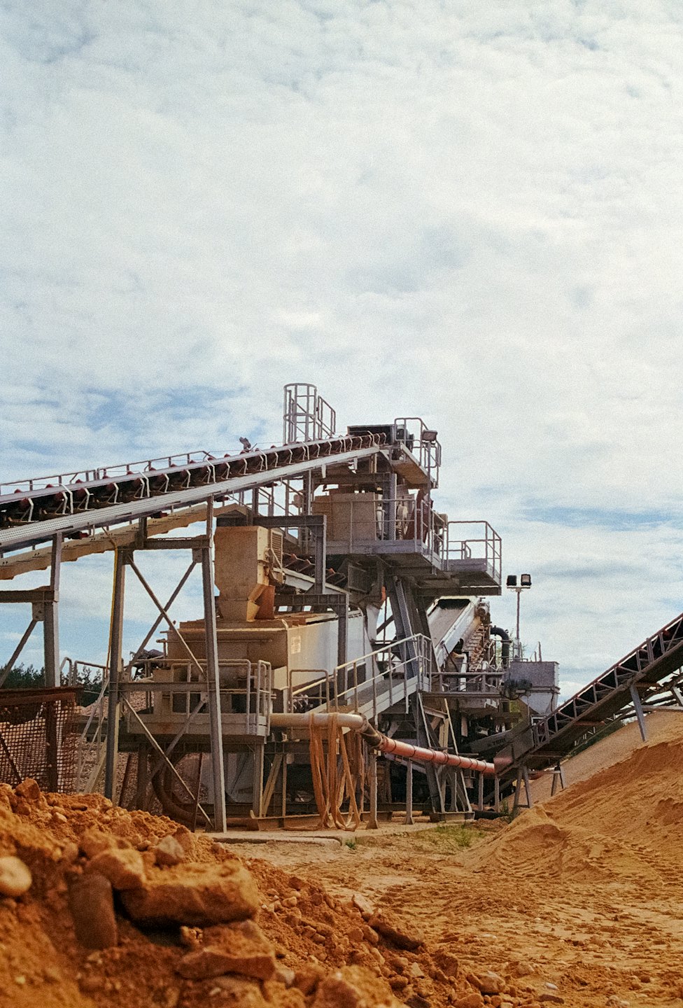 Industrial stone crusher with conveyor belts in an outdoor quarry.
