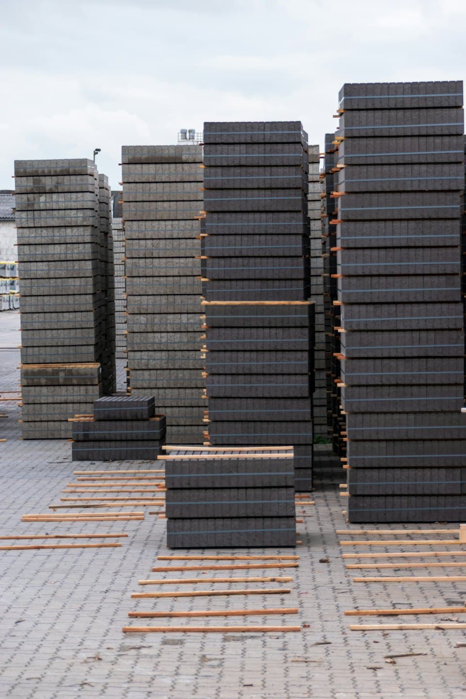 Stacks of grey paving stones on wooden pallets in an outdoor storage yard.