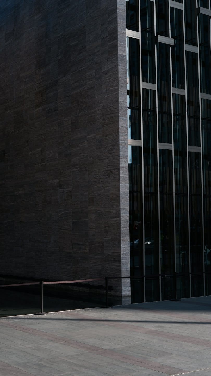 Modern building with a glass facade and stone wall.