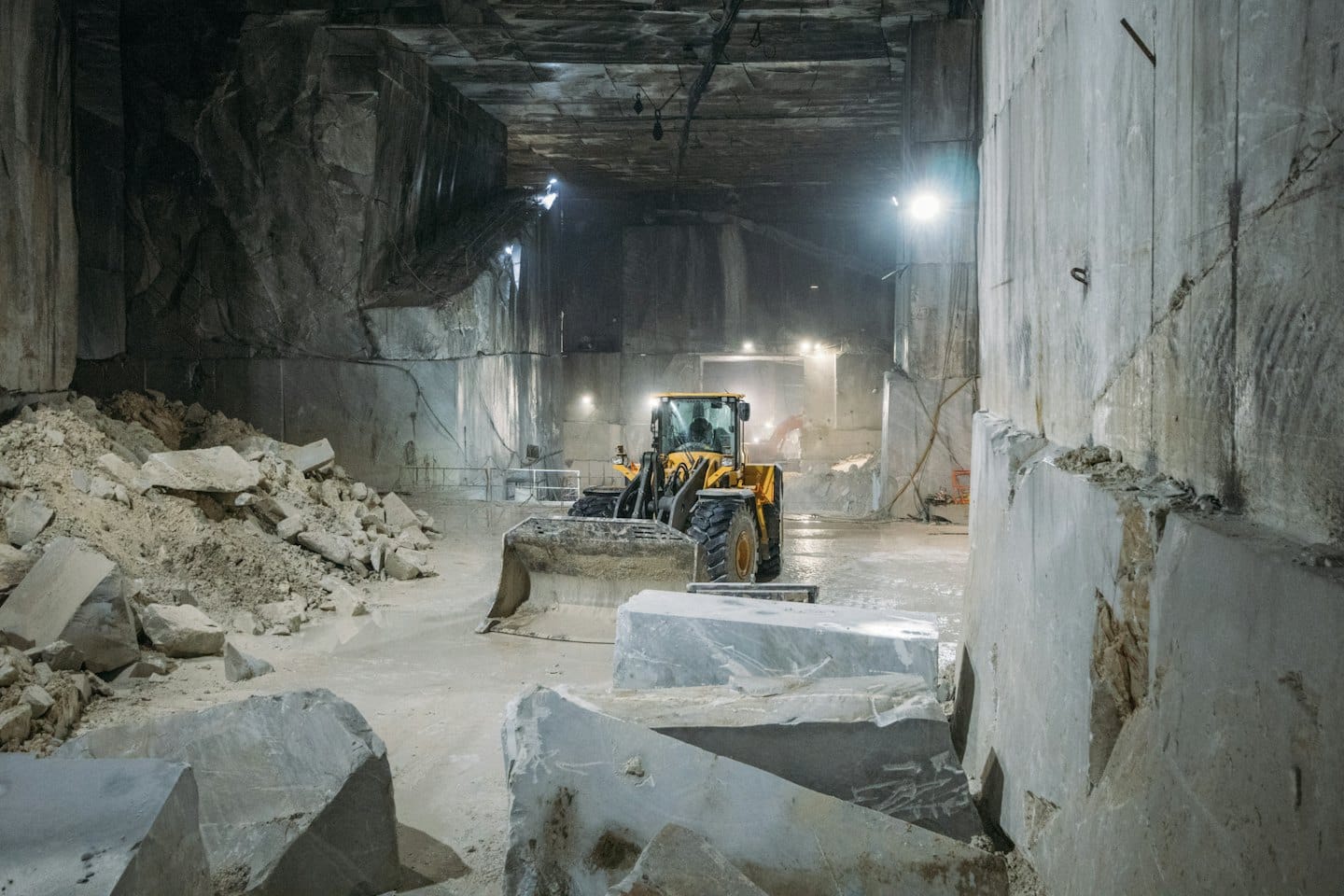 A yellow front-end loader parked in an underground marble quarry.