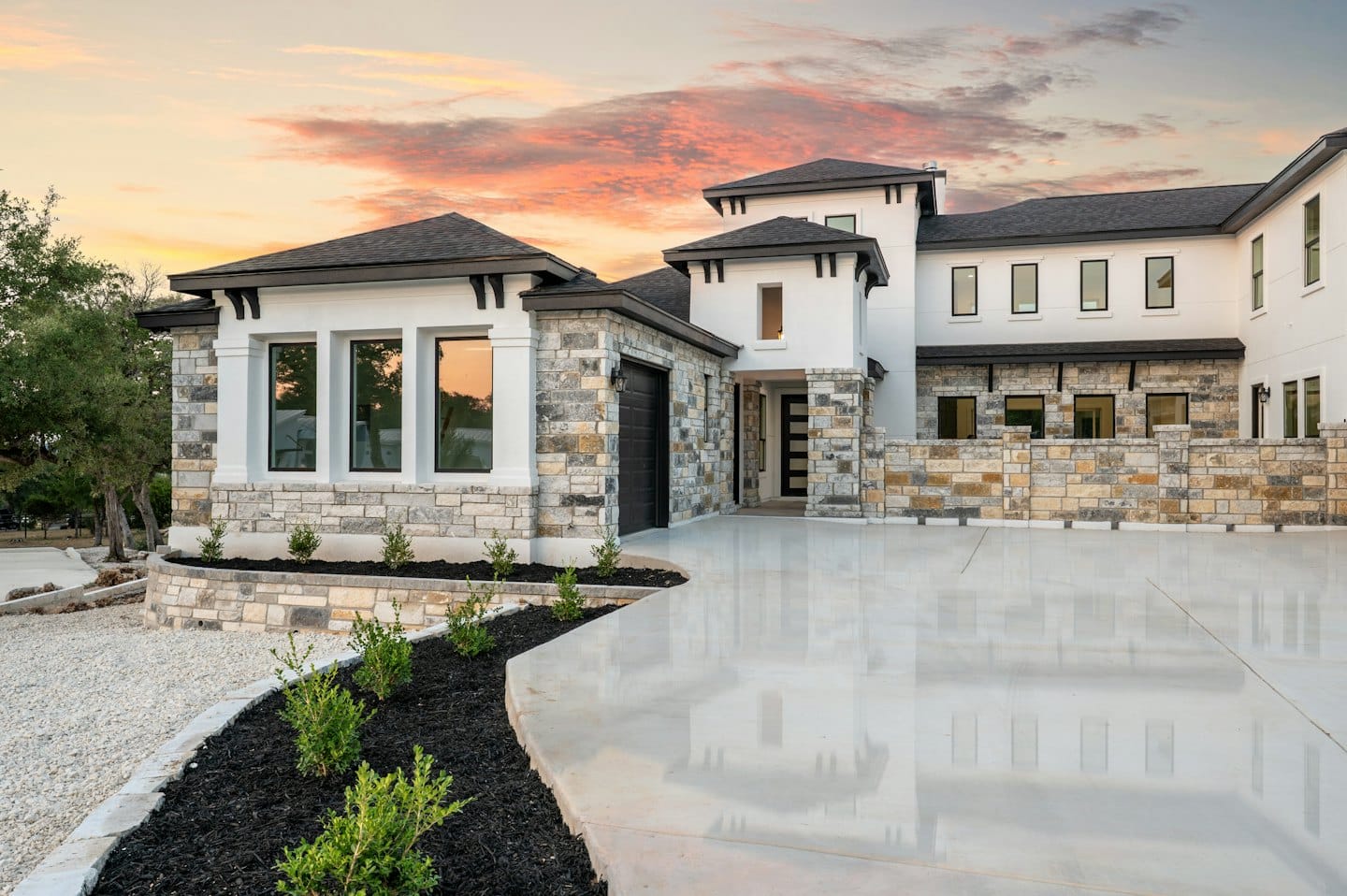 Modern luxury home with stucco and stone at sunset.